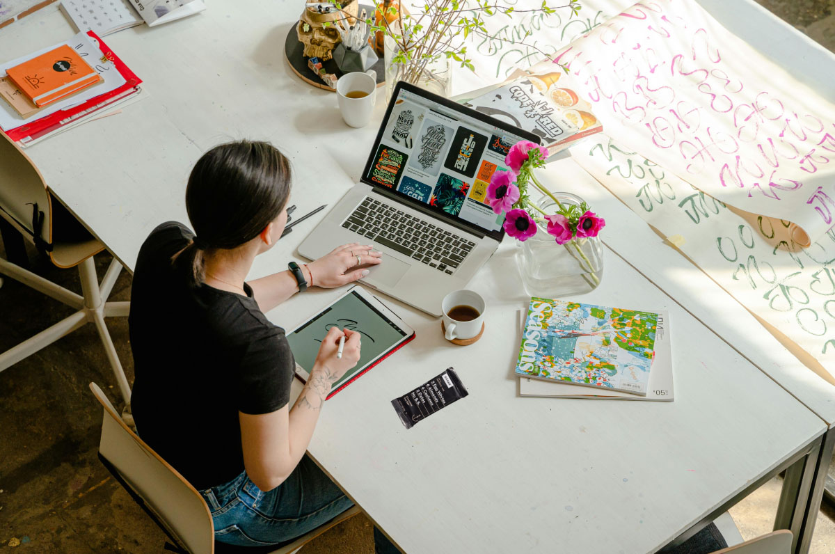 A woman working at a computer desk with an RXBAR on the desk.