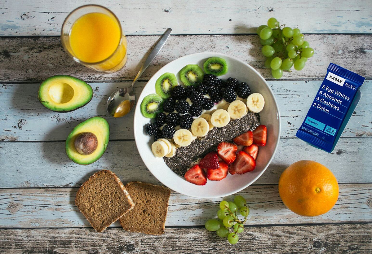 An assortment of foods with an RXBAR on the desk.