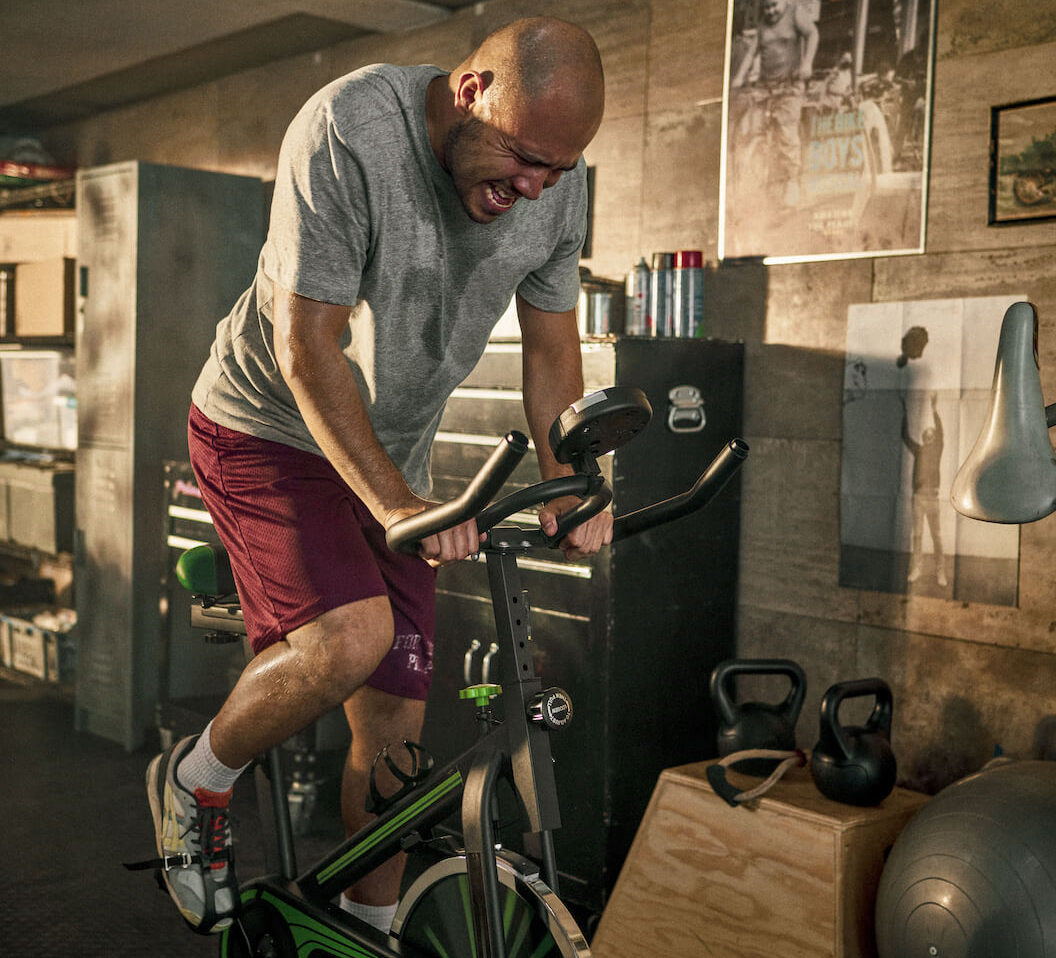 Man on exercise bike exerting maximum effort with No B.S - RXBAR products