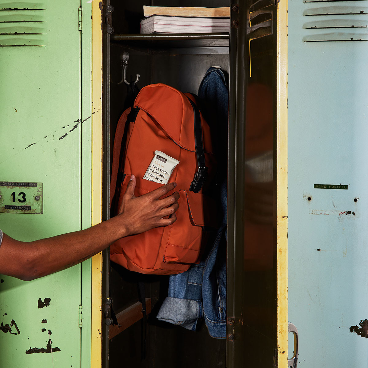 A person reaching for an RXBar in a backback in a school locker.